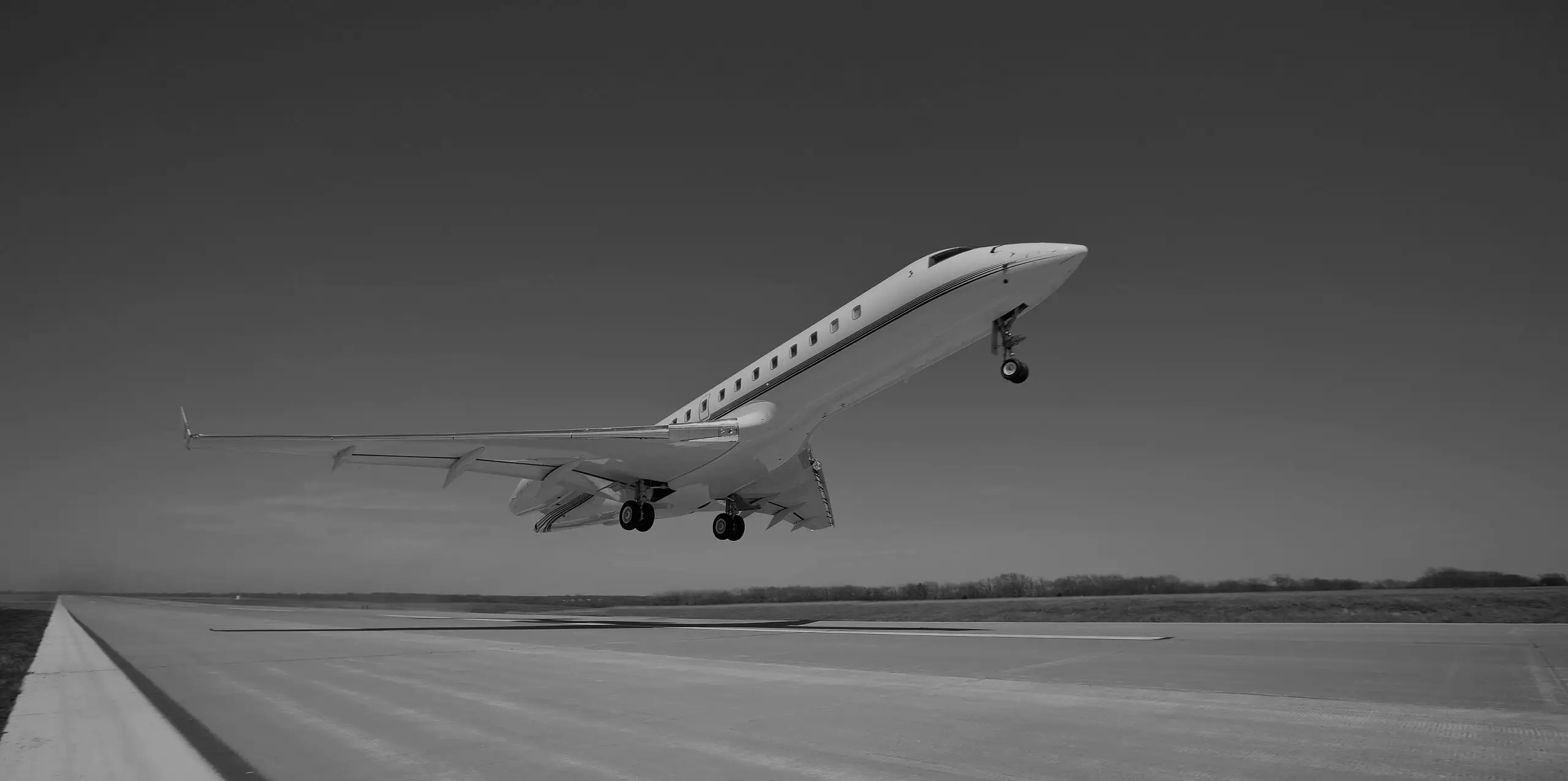 A large-cabin business jet lifting off a runway